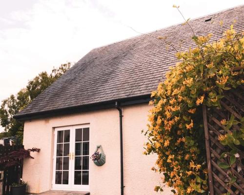 a white house with a black roof and a window at Ardbrae Cottage in Daviot
