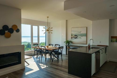 a kitchen and dining room with a table and chairs at Luxury Coffee Bean Condo - Pool & Stunning View in Baie-Saint-Paul