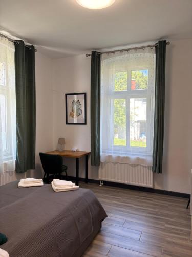 a bedroom with a bed and a desk and a window at Willa Pod Platanem in Bytów