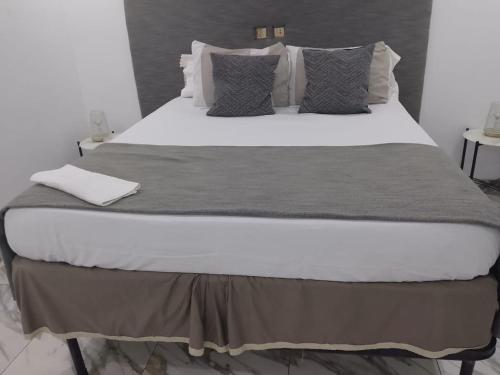 a large bed with white sheets and gray pillows at Immobilier Du siecle in Abidjan