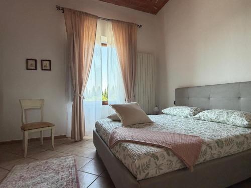 a bedroom with a bed and a window with a chair at Del Rio Palace Guest House in Certaldo