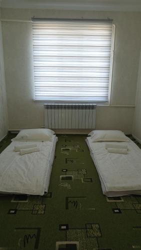 two beds in an empty room with a window at Bilalguesthouse in Dzhangyaryk