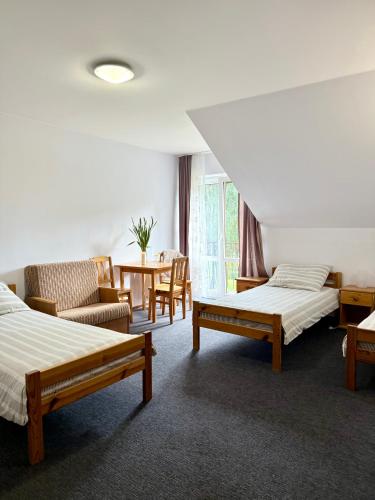 a room with two beds and a table and chairs at Pokoje Alina, 500m do morza ze śniadaniem in Grzybowo