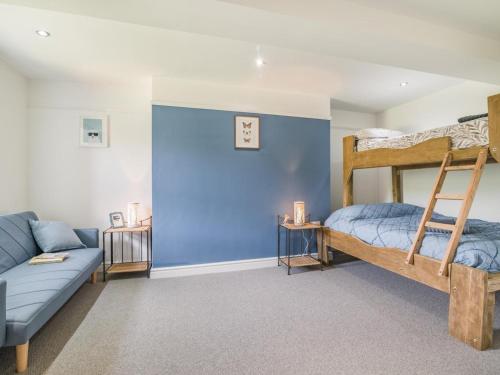 a bedroom with bunk beds and a couch at 3 Bed in Brecon oc-92320 in Llandeilor-Fan