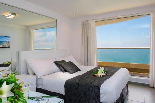a bedroom with a bed and a large window at AREAN Hotel Bat Yam in Bat Yam
