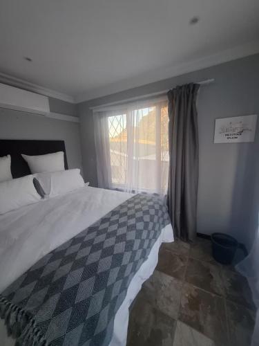 a bedroom with a large bed and a window at The Cottage Eplazini in Port Shepstone