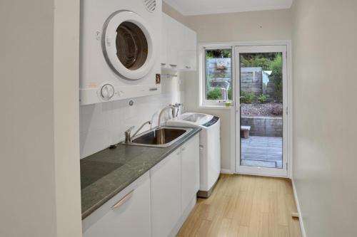 a white kitchen with a sink and a window at Bliss by the Bay in Metung