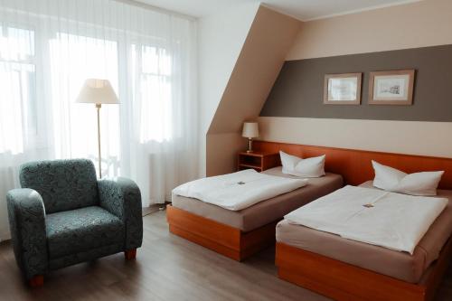a hotel room with two beds and a chair at Schlossberghotel Greiz in Greiz