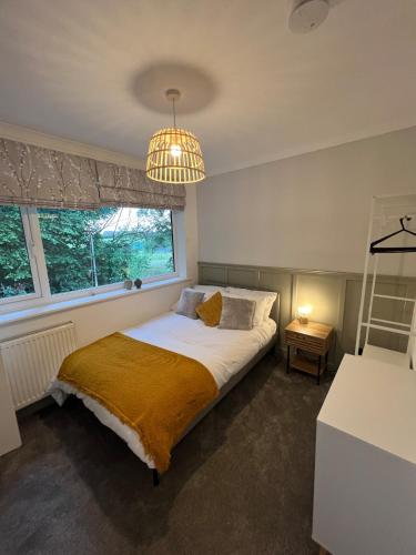 a bedroom with a bed and a chandelier at Melton House in Houghton Regis