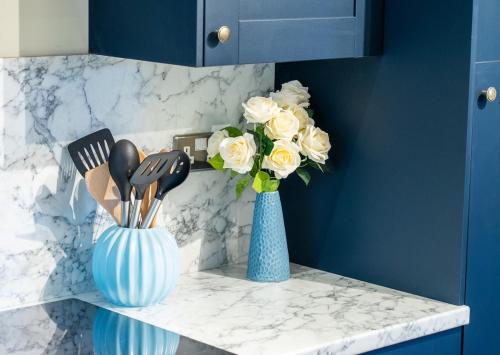 two blue vases with utensils on a counter with flowers at Melton House in Houghton Regis