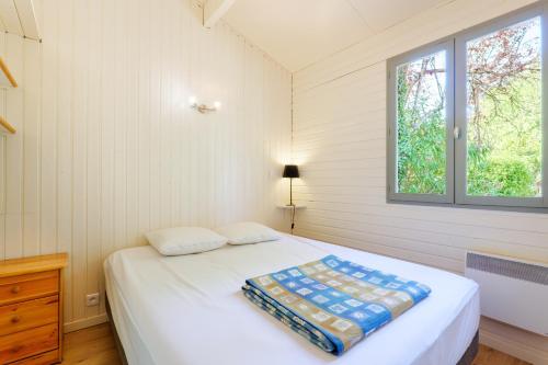 a white bedroom with a bed and a window at Chalet confort 4 piscine partagée in Les Vans