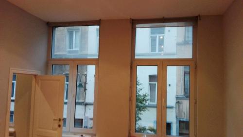 a room with three windows in a building at Central Yellow Apartment in Brussels