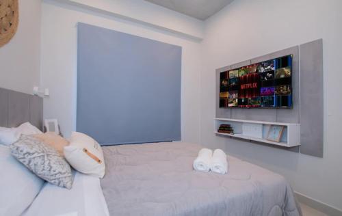 a white bedroom with a bed with two towels on it at Peaceful Stay with Rooftop Pool Access in Fernando de la Mora