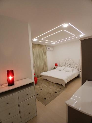 a bedroom with a white bed and a red light at California Stay in Amman