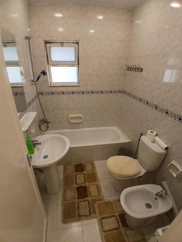 a bathroom with a toilet and a tub and a sink at California Stay in Amman