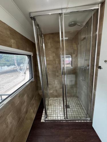 a shower with a glass door in a bathroom at Roulotte Beach São Tomé in Triunfo