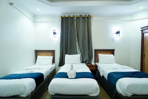 three beds in a hotel room with a cat sitting on them at فندق ندى الفيروز in Az Zāhir
