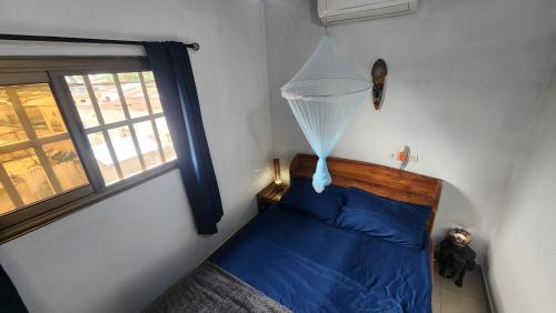 a bedroom with a bed with blue sheets and a window at Le perchoir bleu in Lomé