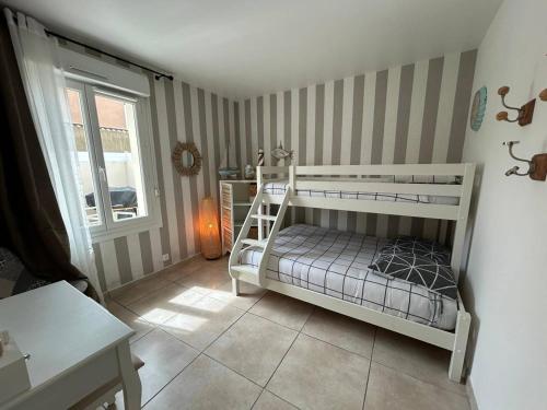 a bedroom with a white bunk bed in a room at Desbo in Valras-Plage