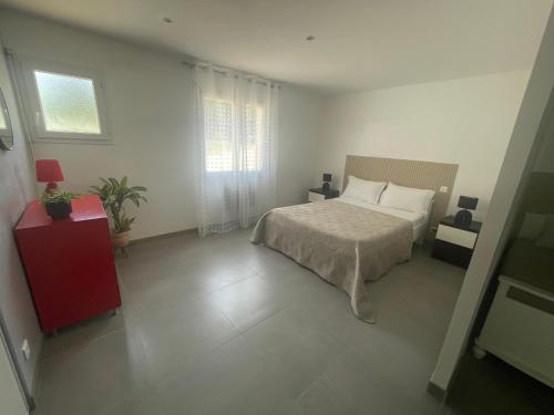 a white bedroom with a bed and a red cabinet at Apartment 65 m2 SE Rez de Jardin 2 chambres in Varetz