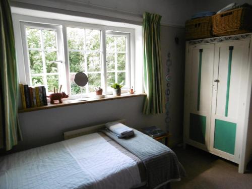 a bedroom with a bed and two windows at 2 Little Meadow Cottages in Dartmouth