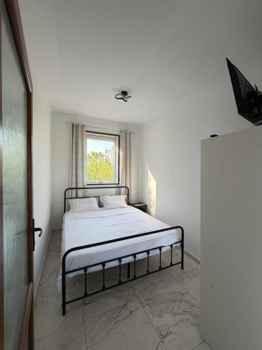 a white bedroom with a bed and a window at Sea view Kastri in Nei Poroi