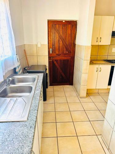a kitchen with a sink and a wooden door at Arise self catering in Burgersfort