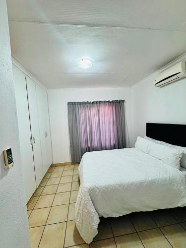 a bedroom with a white bed and a window at Arise self catering in Burgersfort