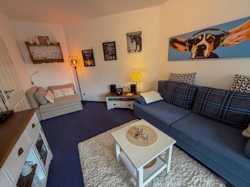 a living room with a blue couch and a dog on the wall at Haus Sachsensteinblick in Bad Sachsa