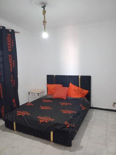 a bedroom with a black bed with orange pillows at Aïn turk oran in Aïn El Turk