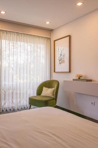 a bedroom with a bed and a chair and a window at 3Encostas in Cabeceiras de Basto