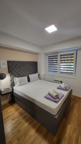 a bedroom with a large white bed with two towels on it at Lazaro Urban Apartment in Skopje
