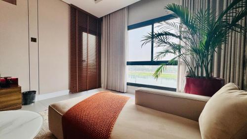a living room with a couch and a palm tree at جناح فاخر بإطلالة على البحيرة وجاكوزي خاص in Al Khobar