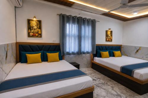 a bedroom with two beds with yellow and blue pillows at Hotel PKD Vrindavan Near 100 Futta Main Road in Vrindāvan