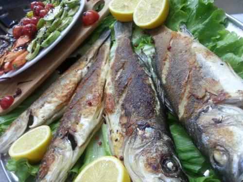 a plate of fish with lettuce and lemon slices at Hotel Mustang in Tirana