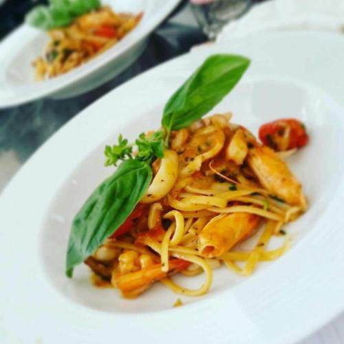 a white plate of pasta with basil leaves on it at Hotel Mustang in Tirana