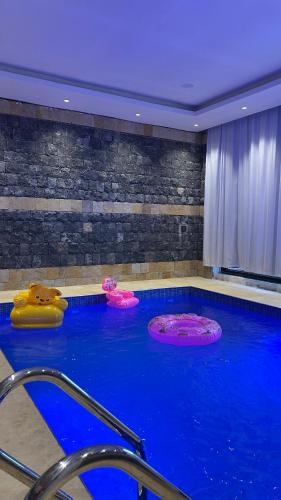 a large swimming pool with three inflatable objects in it at Rawnaq aljabal chalet in Qurayyah