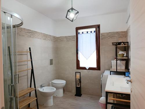 a bathroom with a toilet and a sink and a window at Casa IS JANAS in San Sperate
