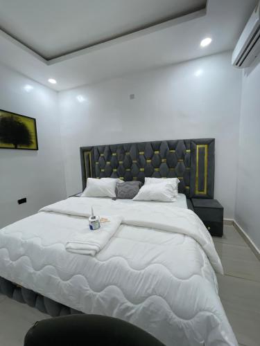 a bedroom with a large white bed with a large headboard at At Kora Apartment and Shortlets in Asaba
