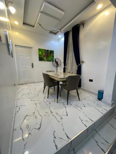 a dining room with a marble floor and a table and chairs at At Kora Apartment and Shortlets in Asaba