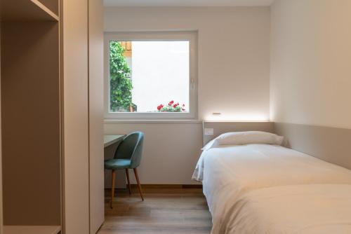 a bedroom with a bed and a chair and a window at Altavista Aura in Molveno