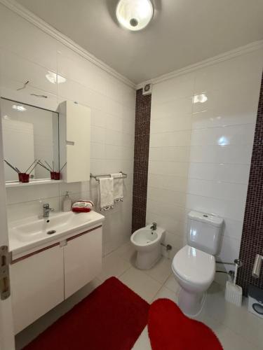 a white bathroom with a toilet and a sink at Duplex in Kosovo Polje