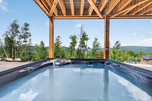 a hot tub in a pavilion with a view of trees at Spa Pool Table Ultimate Comfort - OSE Le Refuge in Saint Come