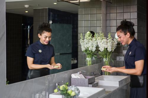 two women standing in front of a bathroom mirror at U Nimman Chiang Mai in Chiang Mai
