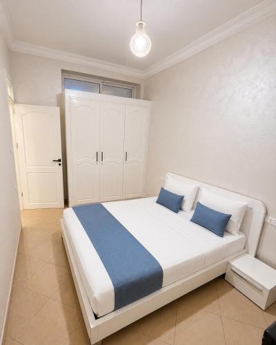 a bedroom with a large white bed with blue pillows at Royal Rif Alhoceima Centre in Al Hoceïma