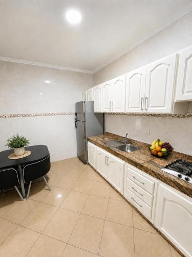 a kitchen with white cabinets and a sink and a table at Royal Rif Alhoceima Centre in Al Hoceïma