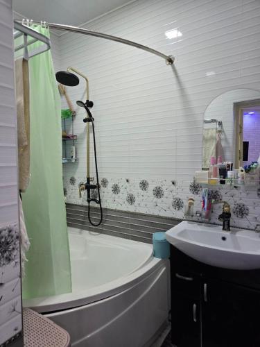 a bathroom with a shower and a tub and a sink at Hamroz apartment in Navoi