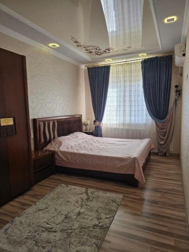 a bedroom with a large bed with blue curtains at Hamroz apartment in Navoi