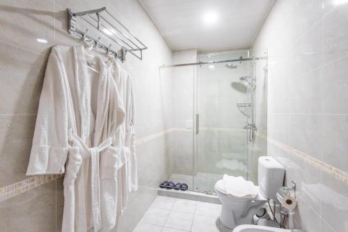 a white bathroom with a shower and a toilet at HUMO Hotel in Stantsiya Kyzyl-Tukumachi