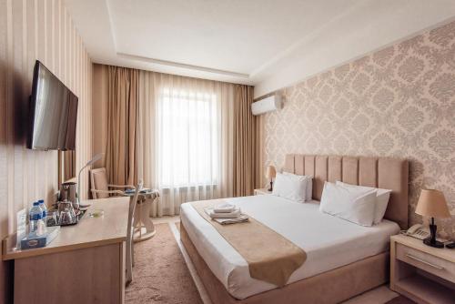 a hotel room with a bed and a desk and a television at HUMO Hotel in Stantsiya Kyzyl-Tukumachi